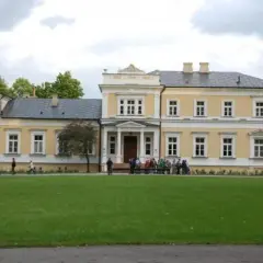 Pałac w Ciechanowcu, jedna z atrakcji regionu, otoczony zielenią. Grupa osób zwiedza teren.