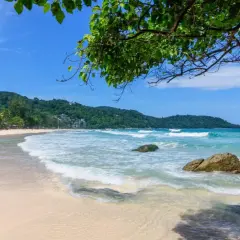 Piękna plaża Kata Beach z turkusową wodą, falami i zielonymi wzgórzami w tle.