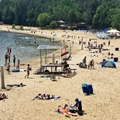 Słoneczna plaża Skorochów tętni życiem. Ludzie kąpią się, opalają i odpoczywają na piasku, ciesząc się letnim dniem.