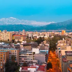 Widok na Santiago, stolicę Chile, z górami w tle. Miasto tętni życiem, a światła uliczne rozświetlają wieczór.