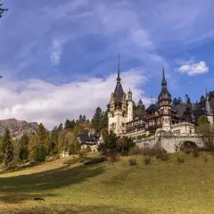 Zamek Peles w Rumunii, malowniczo położony wśród jesiennych drzew. Ceny zwiedzania zamku są przystępne, co czyni go idealnym celem podróży.
