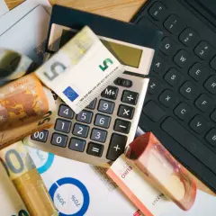 Kalkulator, banknoty euro i klawiatura sugerują analizę cen w Szwecji.