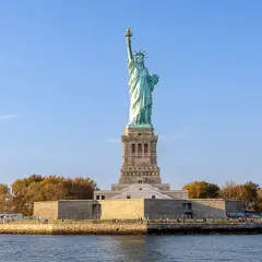 Gdzie jest Statua Wolności? Na wyspie Liberty Island w Nowym Jorku, dumnie wznosi się symbol wolności, otoczona wodą i jesiennymi drzewami.