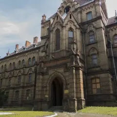 Mokrzeszów pałac, monumentalna budowla z cegły, z charakterystycznymi łukami i wieżyczkami, otoczona zielenią.
