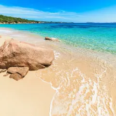 Piękna plaża na Costa Smeralda, Sardynia, z turkusową wodą, złotym piaskiem i skalistym wybrzeżem.
