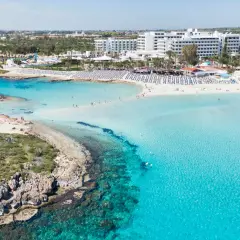 Piękna plaża na Cyprze z turkusową wodą i hotelami. Sprawdź aktualne cypr ceny wakacji!