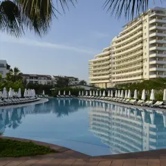 Lara, Turcja: luksusowy hotel z basenem i leżakami pod palmami.