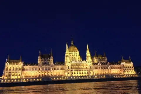 Budynek Parlamentu w Budapeszcie nocą, oświetlony, z odbiciem w Dunaju. Ceny w Budapeszcie mogą być różne, ale widok jest bezcenny.