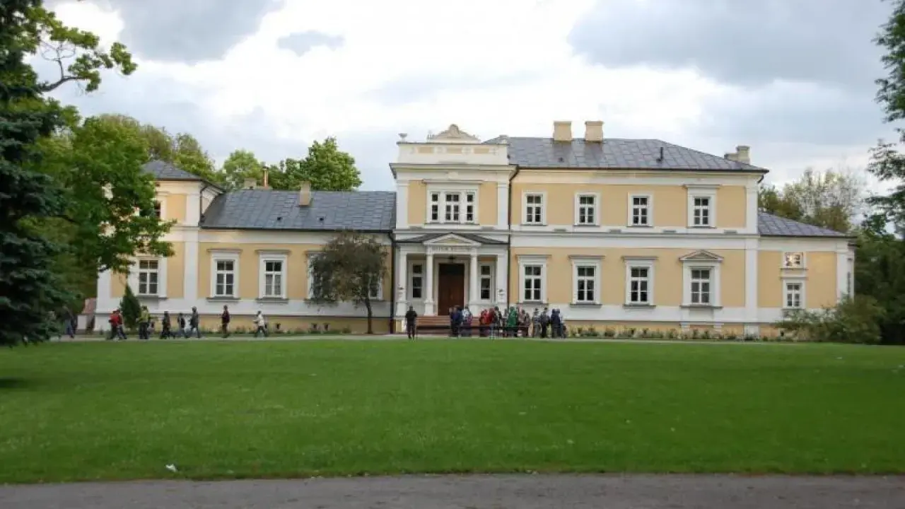 Pałac w Ciechanowcu, jedna z atrakcji regionu, otoczony zielenią. Grupa osób zwiedza teren.