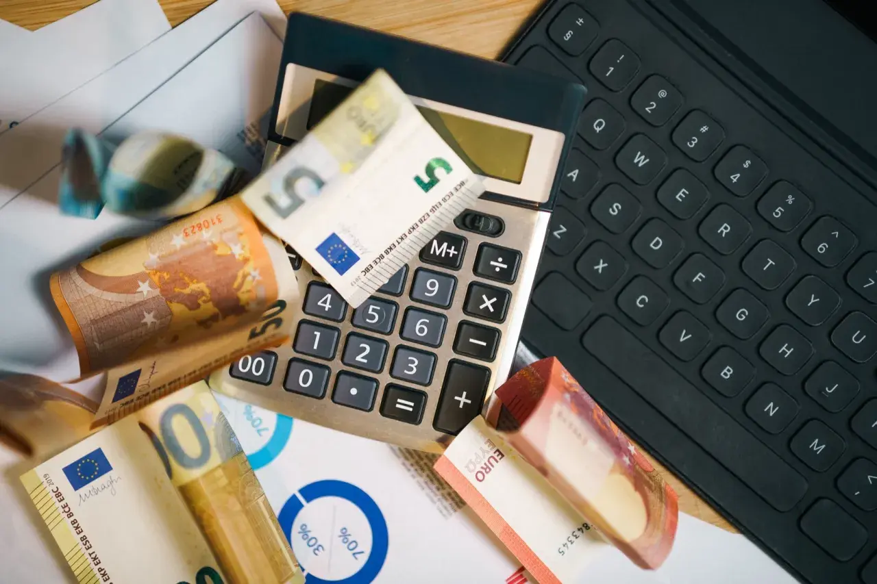 Kalkulator, banknoty euro i klawiatura sugerują analizę cen w Szwecji.