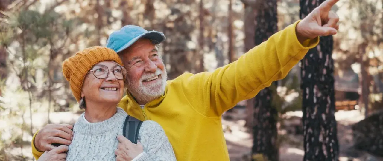 Szczęśliwi seniorzy w lesie, planujący swoje wczasy dla emerytów z dojazdem.
