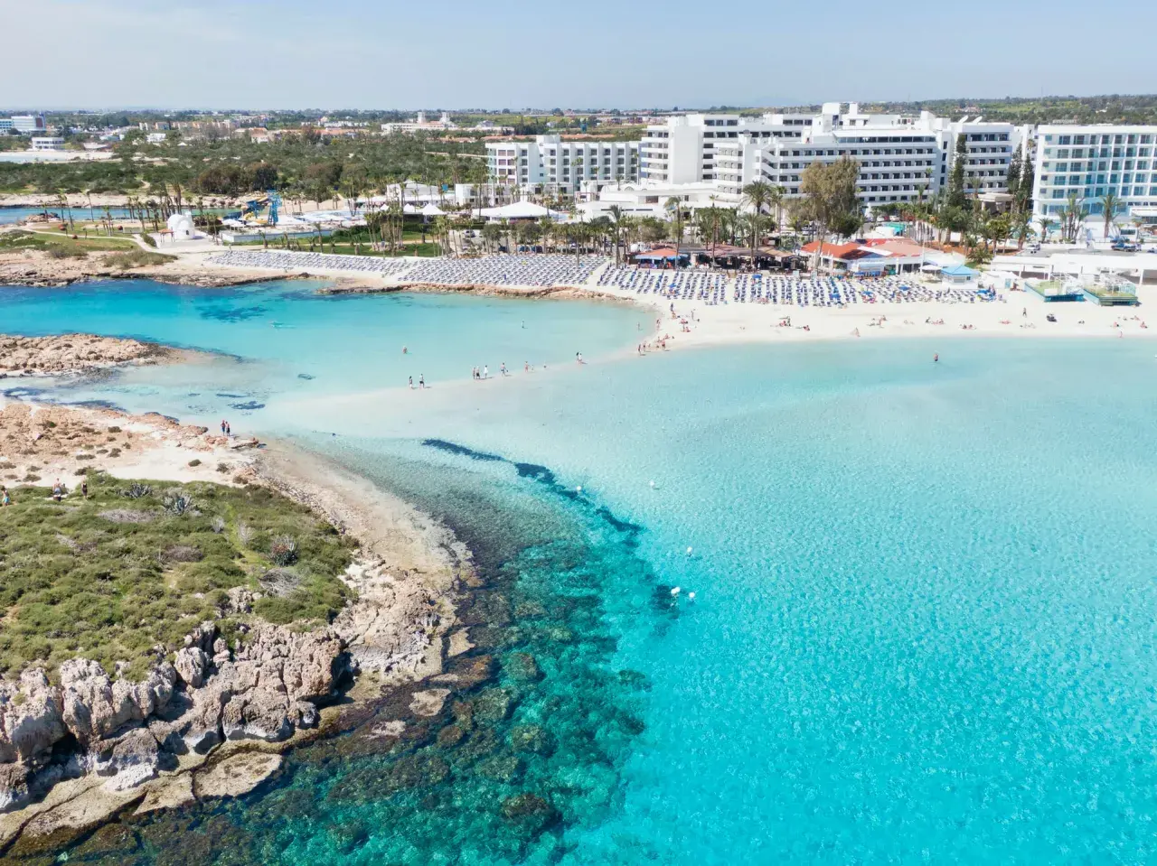Piękna plaża na Cyprze z turkusową wodą i hotelami. Sprawdź aktualne cypr ceny wakacji!