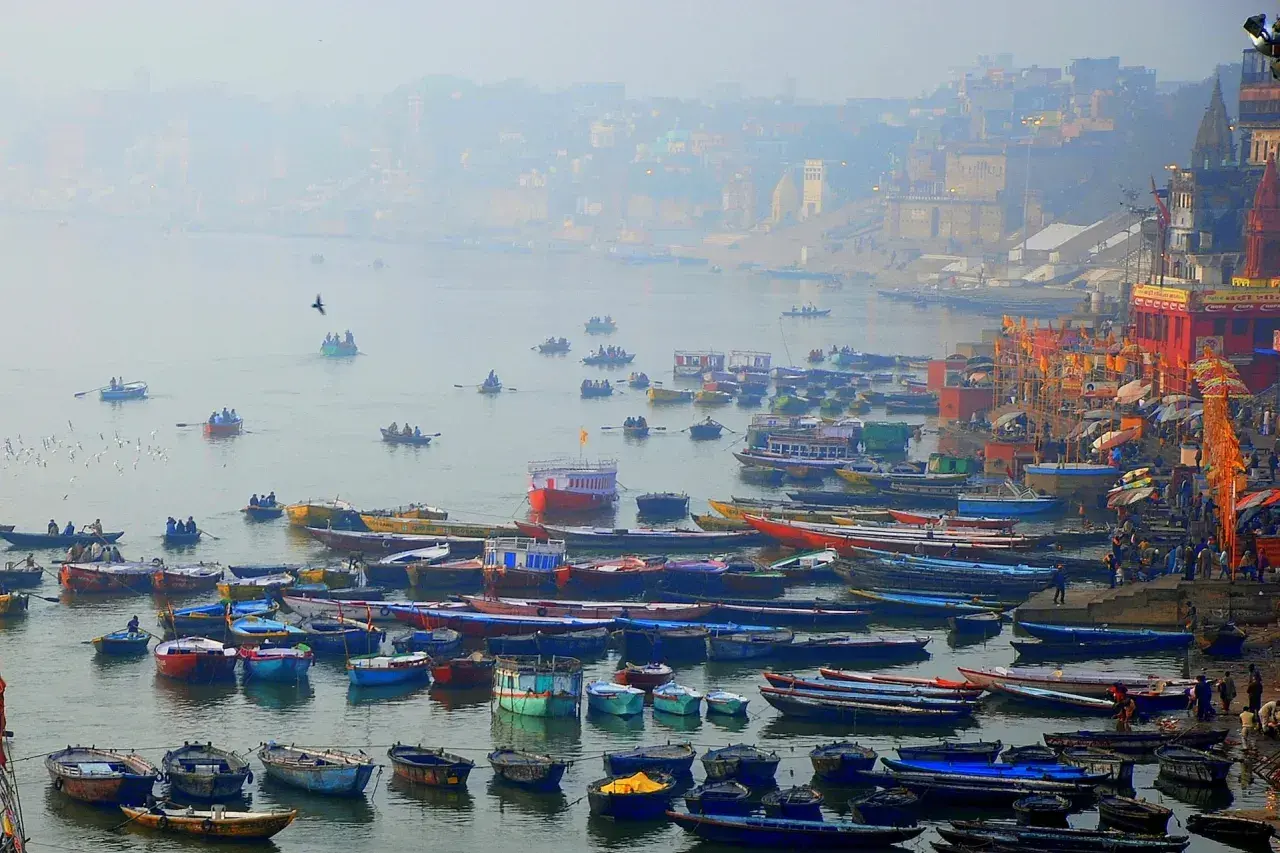 Łodzie na rzece Ganges, w tle mgliste miasto i świątynie.