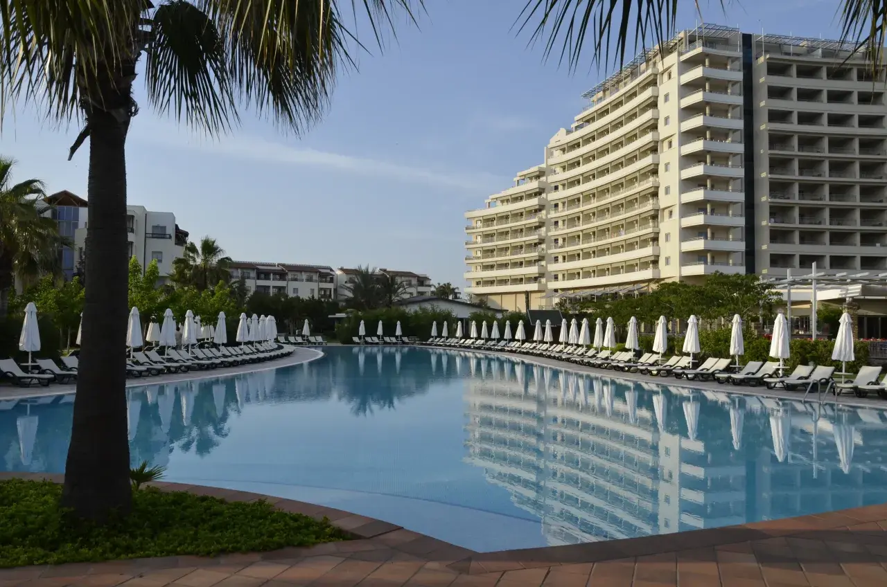Lara, Turcja: luksusowy hotel z basenem i leżakami pod palmami.