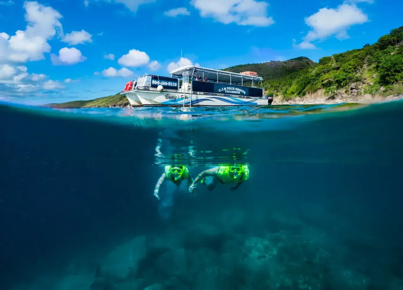 Dwie osoby w maskach do snorkelingu pływają pod wodą, podczas gdy łódź wycieczkowa 