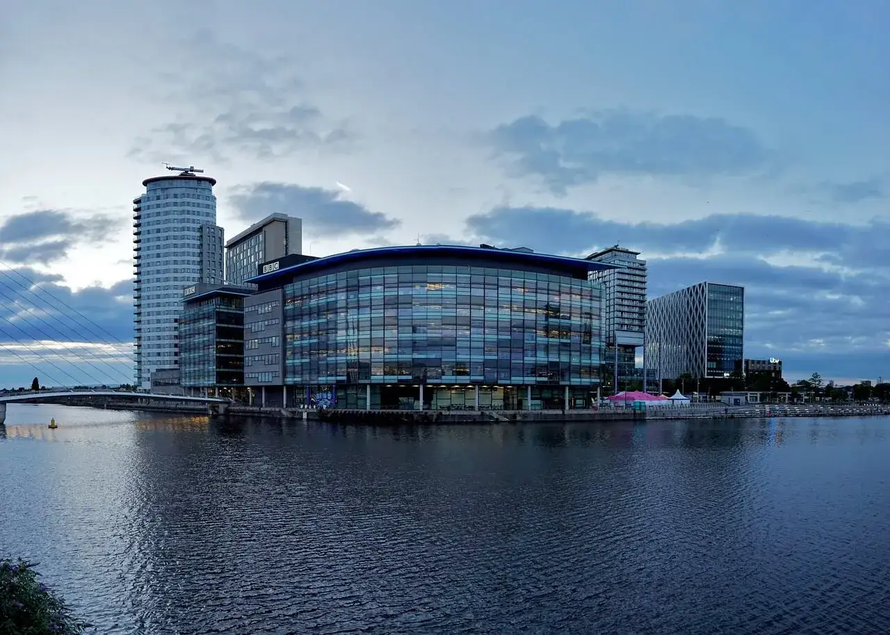 Nowoczesne budynki nad wodą, w tym siedziba BBC, tworzą malowniczy widok na Manchester miasto.
