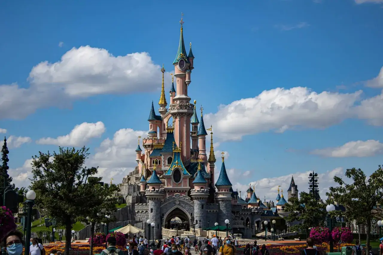 Bajkowy zamek w Disneylandzie, cel wspaniałej itaka wycieczki do Paryża samolotem. Tłumy turystów pod błękitnym niebem.